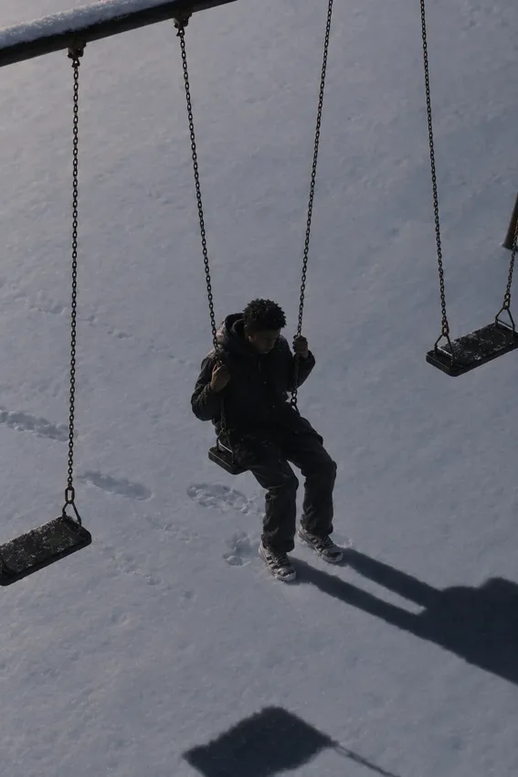 A child on a swing, with long shadows across the ground